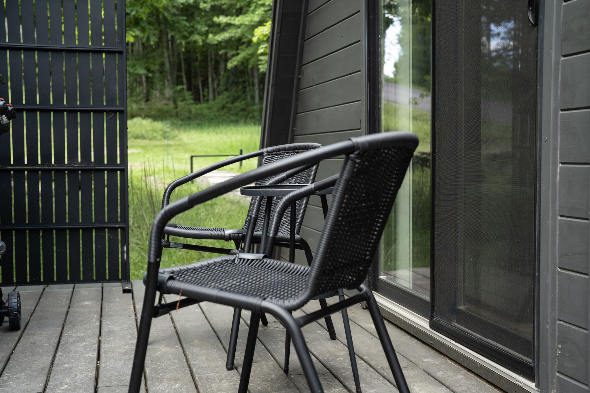 A black metal chair with a mesh backrest on a wooden deck.
