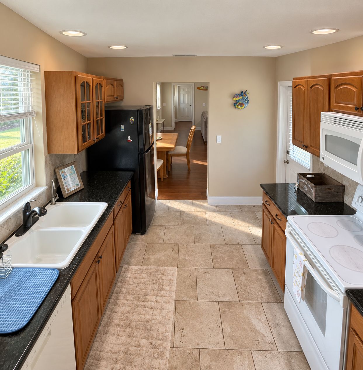 A kitchen with wooden cabinets, a black refrigerator, a white stove, and a dining area in the background.
