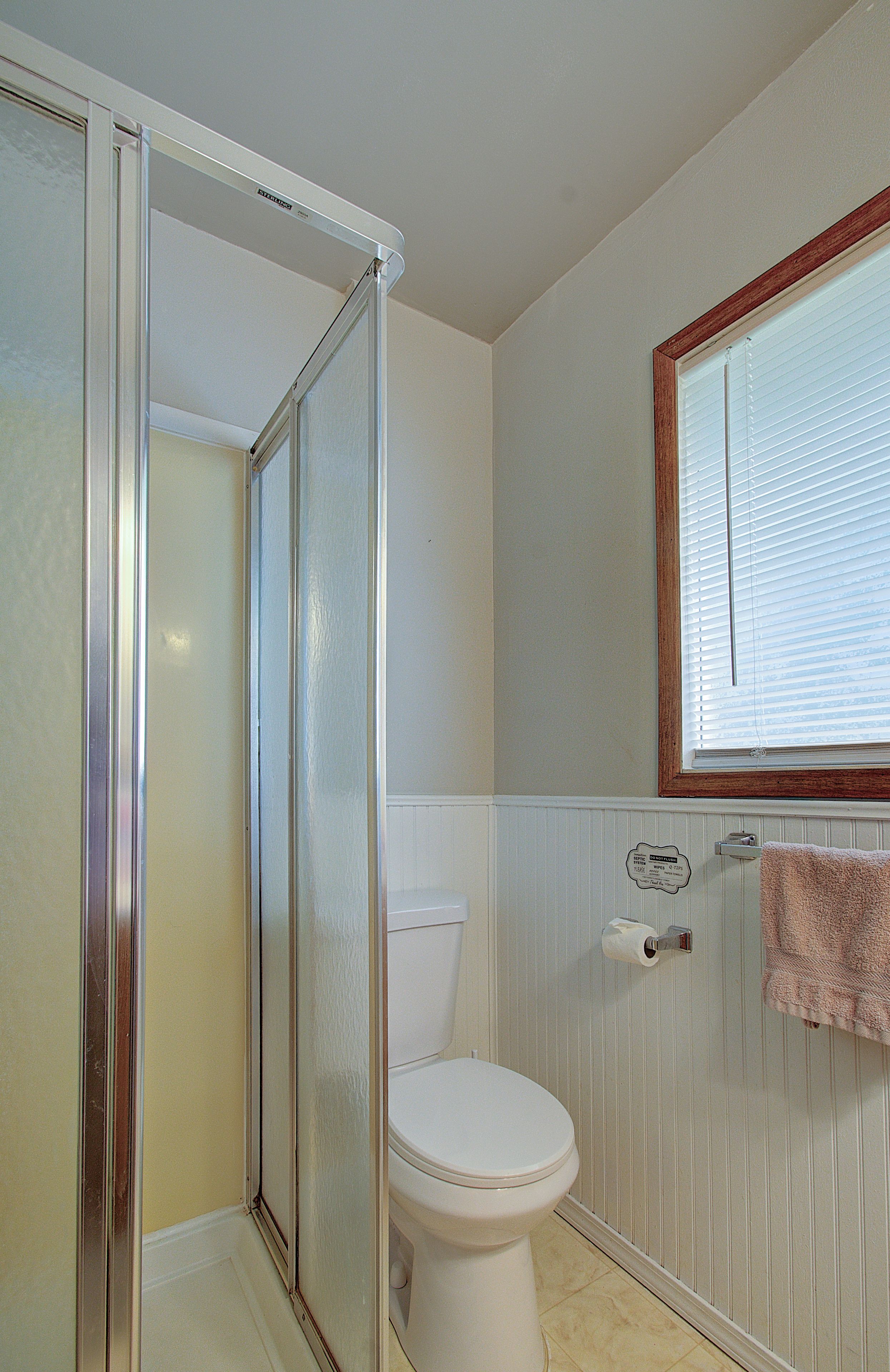 Une salle de bain avec une douche, des toilettes et une serviette suspendue à un porte-serviettes.