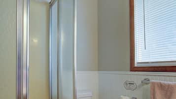 Une salle de bain avec une douche, des toilettes et une serviette suspendue à un porte-serviettes.