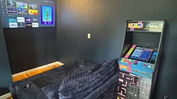 A room with a bed, a wall-mounted TV, and a gaming console.