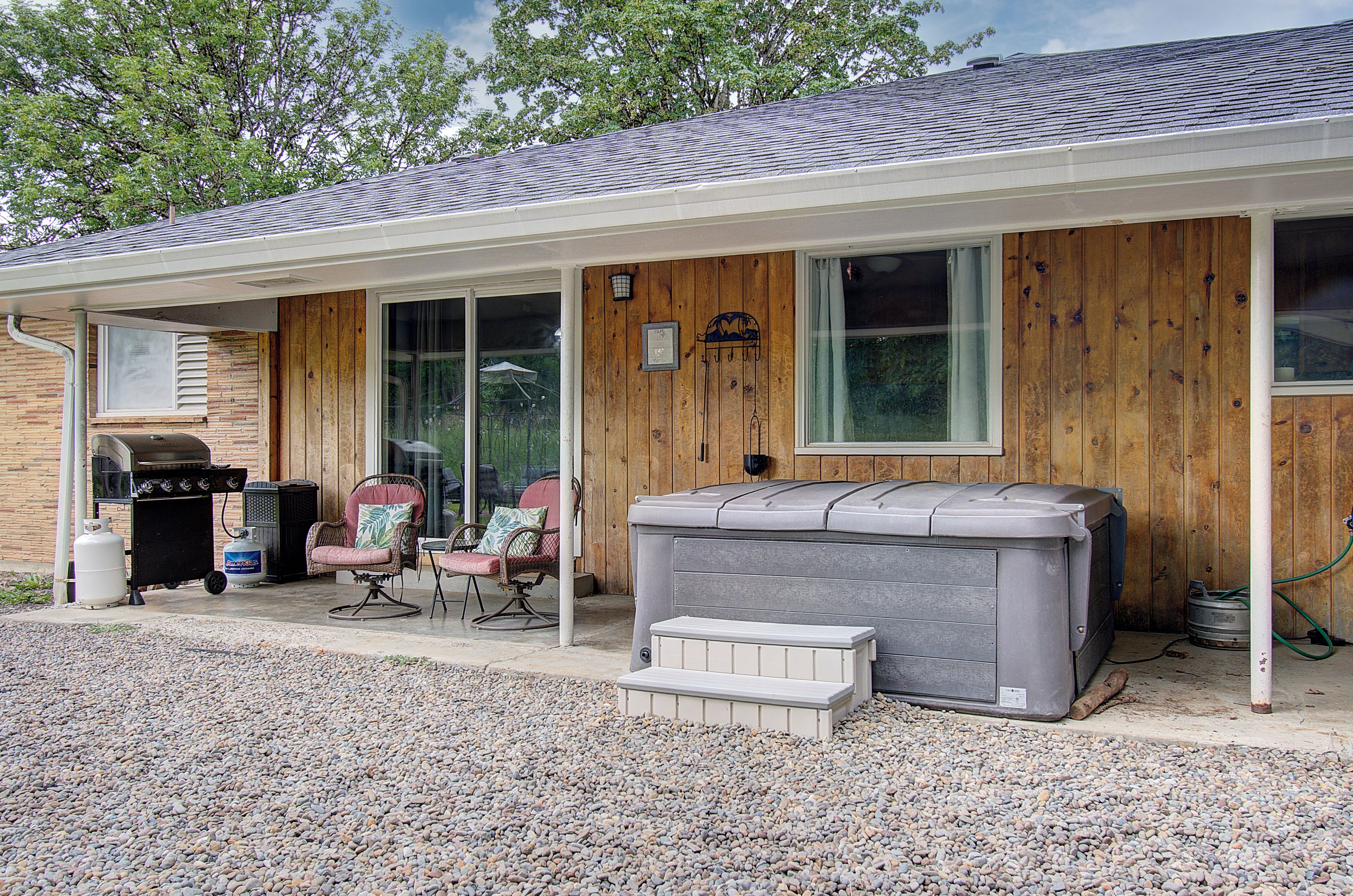 A house with a covered porch, a grill, two chairs, and a large water heater.