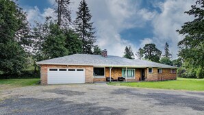 Une maison de plain-pied avec un garage, une véranda et une allée gravillonnée.