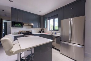 Eine moderne Küche mit dunklen Schränken, einem Edelstahlkühlschrank und einer Mikrowelle.