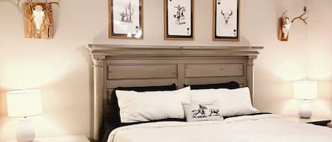A bedroom with a bed, nightstands, a ceiling fan, and wall-mounted artwork.