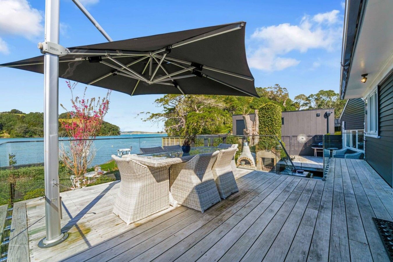 A wooden deck with outdoor furniture, a large umbrella, and a view of a body of water.