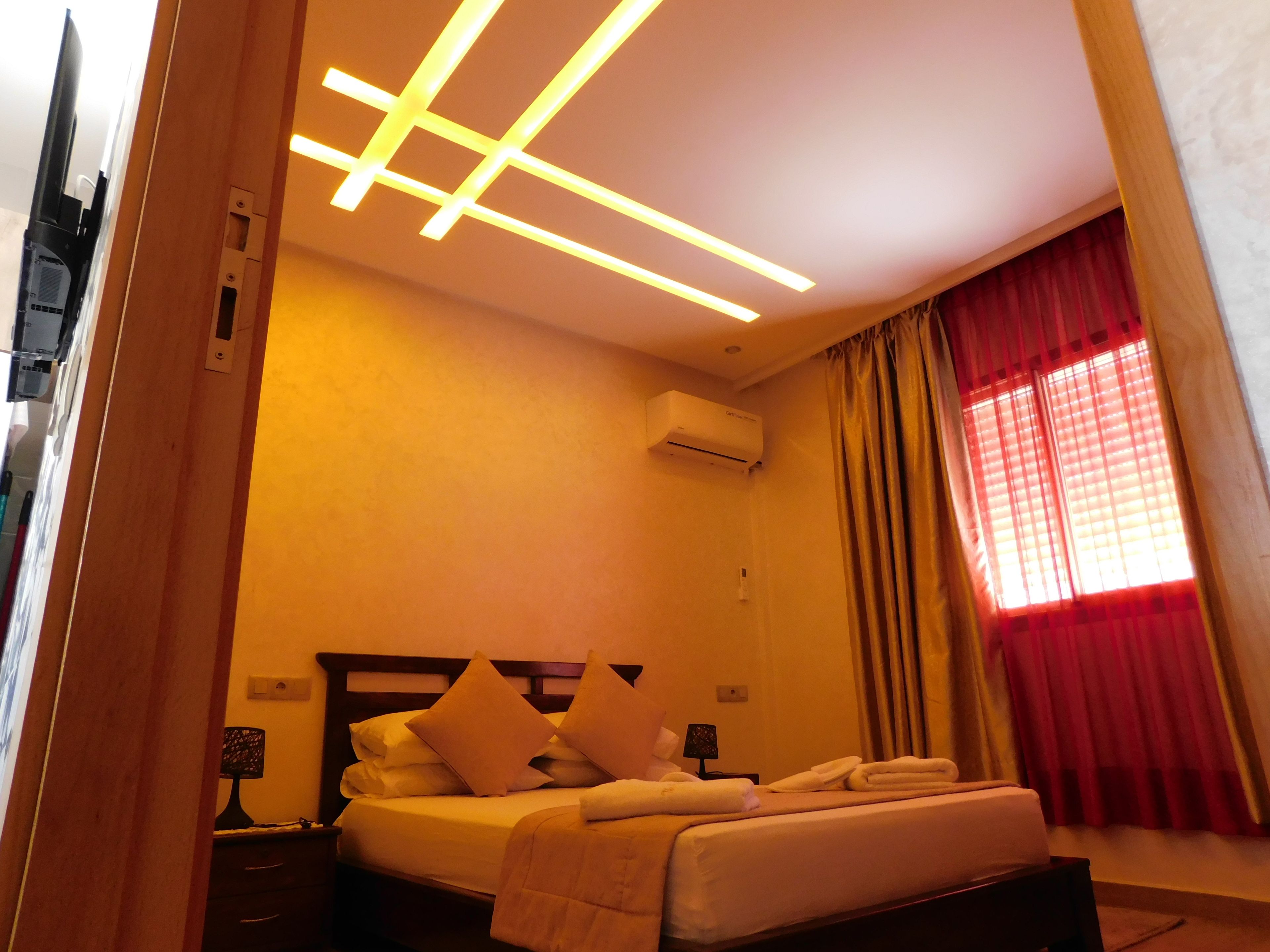 Een hotelkamer met een bed, nachtkastjes, een airconditioning en een raam met gordijnen.