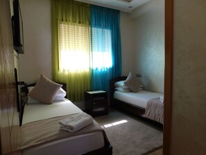 Une chambre d’hôtel avec deux lits, une table de chevet et un téléviseur.