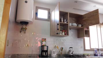 Una cocina con estufa a gas, cafetera, hervidor y armarios de madera.