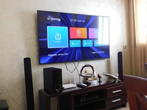 A flat-screen TV mounted on a wall displaying a user interface with options for live TV, movies, and series.