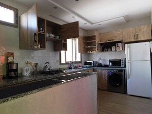 A modern kitchen with wooden cabinets, a built-in microwave, a refrigerator, and a washing machine.