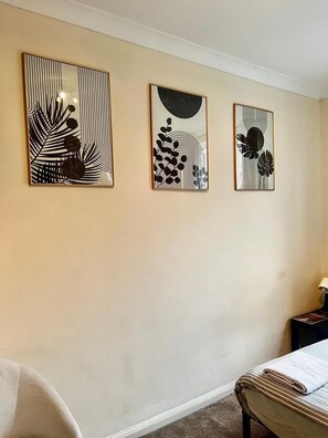 A hotel room with a bed, a nightstand, and three wall-mounted artworks. - Apartment Sleeps 4 Near Station (London)