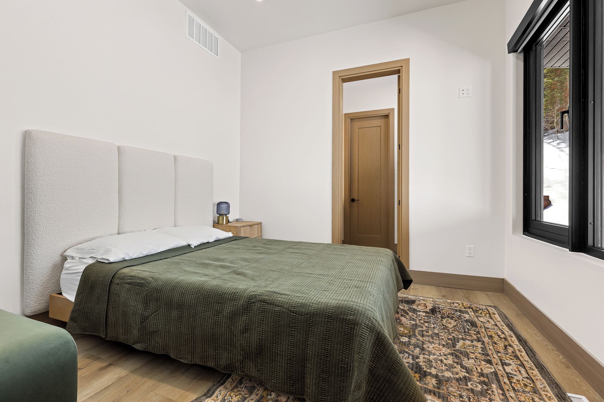 Ein Schlafzimmer mit einem Bett, einem Nachttisch, einer Tür und einem Fenster.