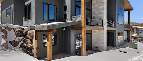 Una casa moderna de dos pisos con fachada de piedra, ventanas amplias y terraza de madera.