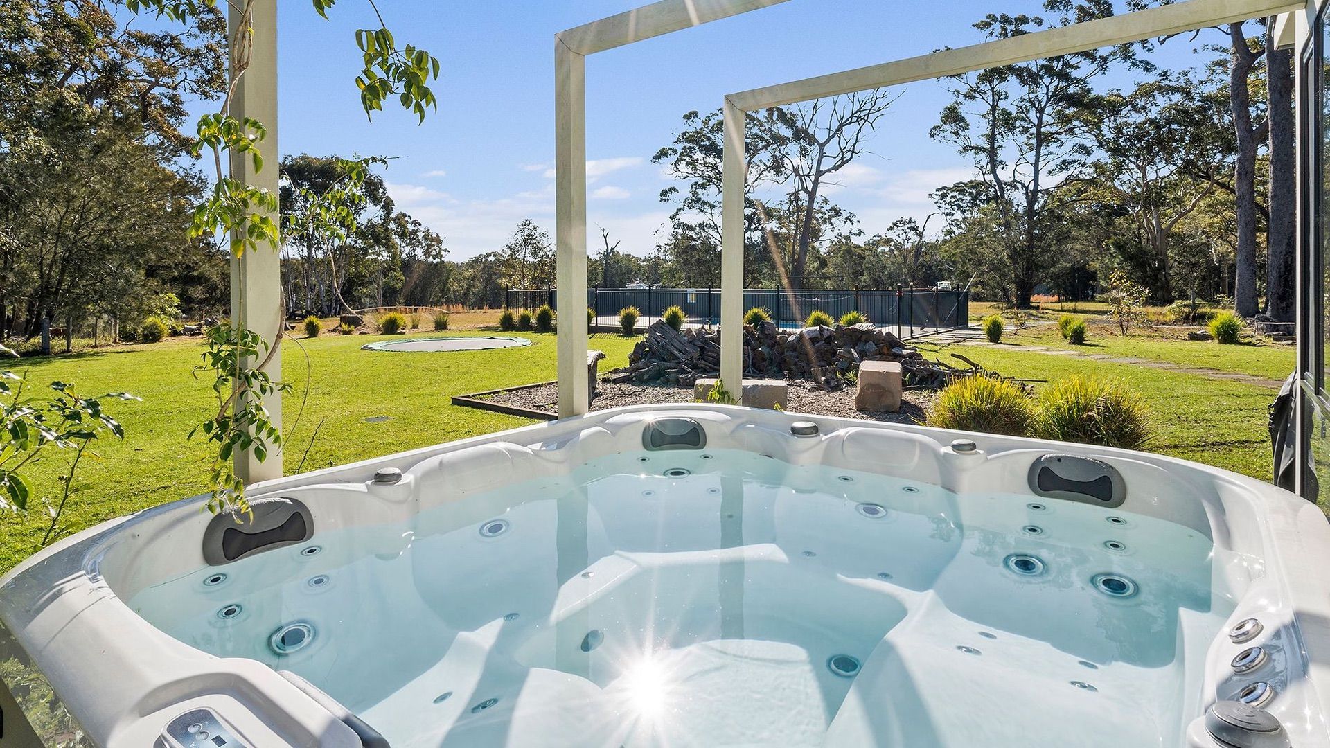 Un jacuzzi con vistas despejadas a un jardín ajardinado y una valla al fondo.