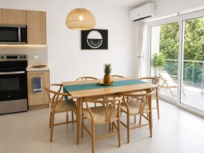 Una cocina moderna con comedor, una lámpara colgante y un equipo de aire acondicionado.