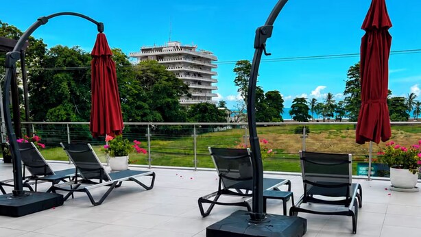 Buitenteak fauteuils met parasols, uitzicht op een gebouw en een aangelegde tuin.