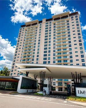 Un hotel de varios pisos con fachada moderna, entrada cubierta y un letrero que indica servicios 'Live'.