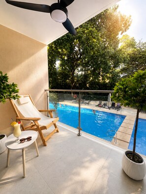 Zona junto a la piscina con piscina, sillas de descanso, una mesa con una bebida y un ventilador de techo.