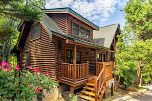 A log cabin with a porch, a staircase, and a stone foundation. - Boujie Bears Den | 5 Kings Mtn Views Hot Tub Pool (Pigeon Forge)