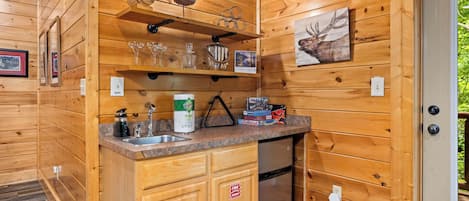 L’intérieur d’une cabane en bois comprend un espace cuisine équipé d’un évier, de placards et d’un réfrigérateur.