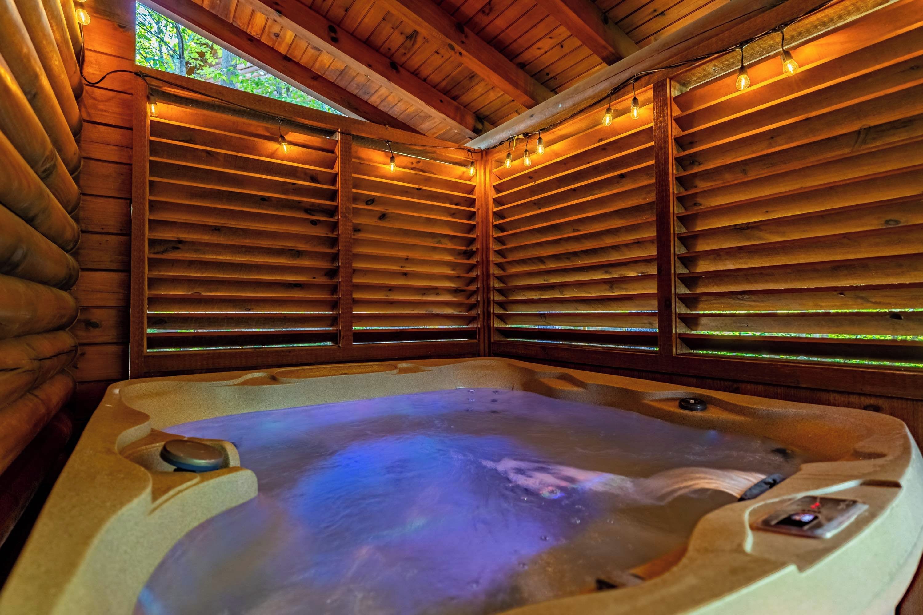 A hot tub in a log cabin with wooden walls and windows.