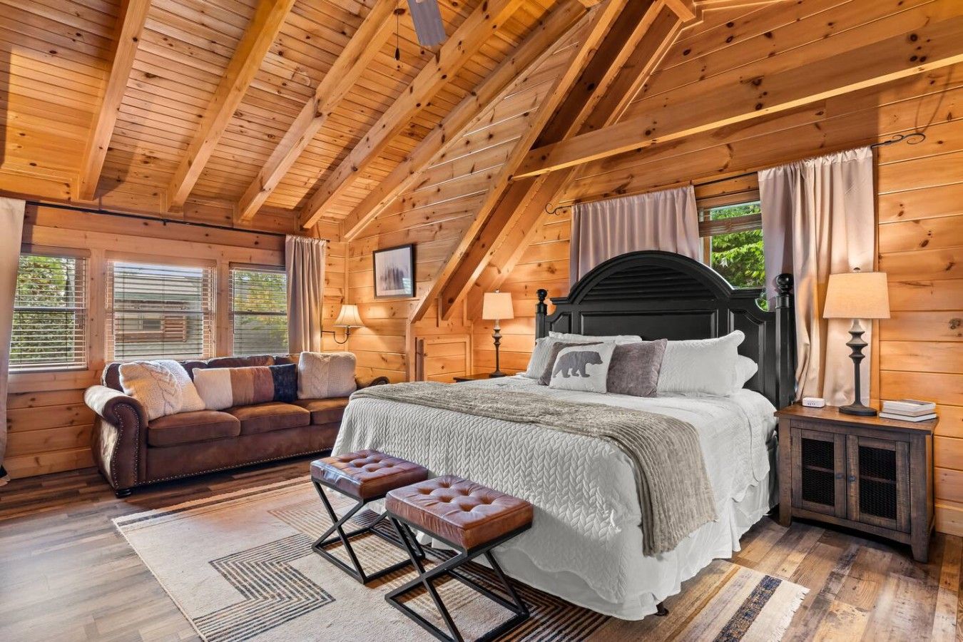 Ein Schlafzimmer einer Holzhütte mit einem Bett, einem Schlafsofa, einem Nachttisch und einem Fenster.