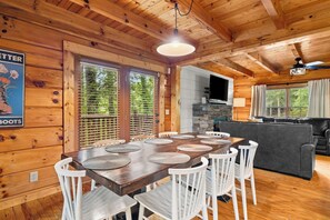 L’intérieur d’un chalet en bois comprend une table à manger, des chaises, un canapé et un téléviseur.