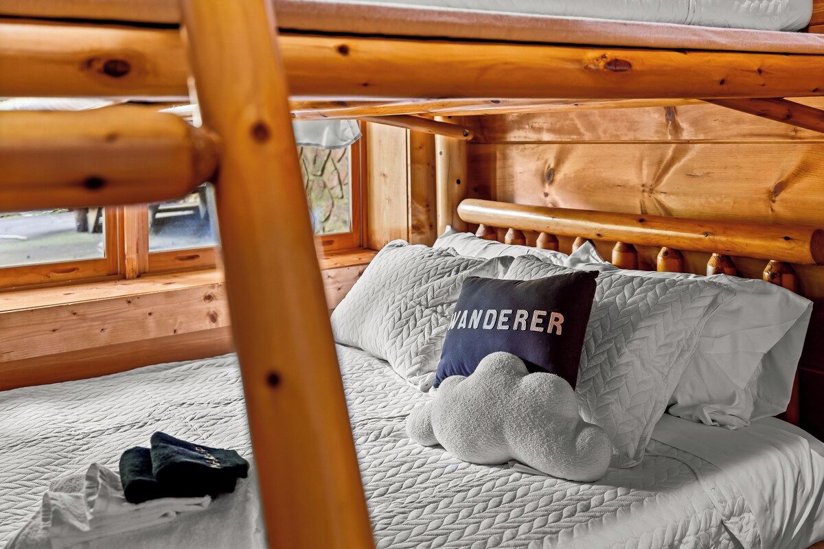 A wooden bunk bed with a quilted mattress and a pillow with the word 'WANDERER' on it.
