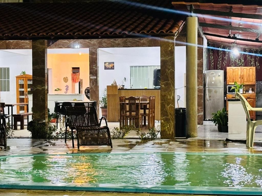 A covered outdoor area with a pool, seating, and a kitchen area visible in the background.