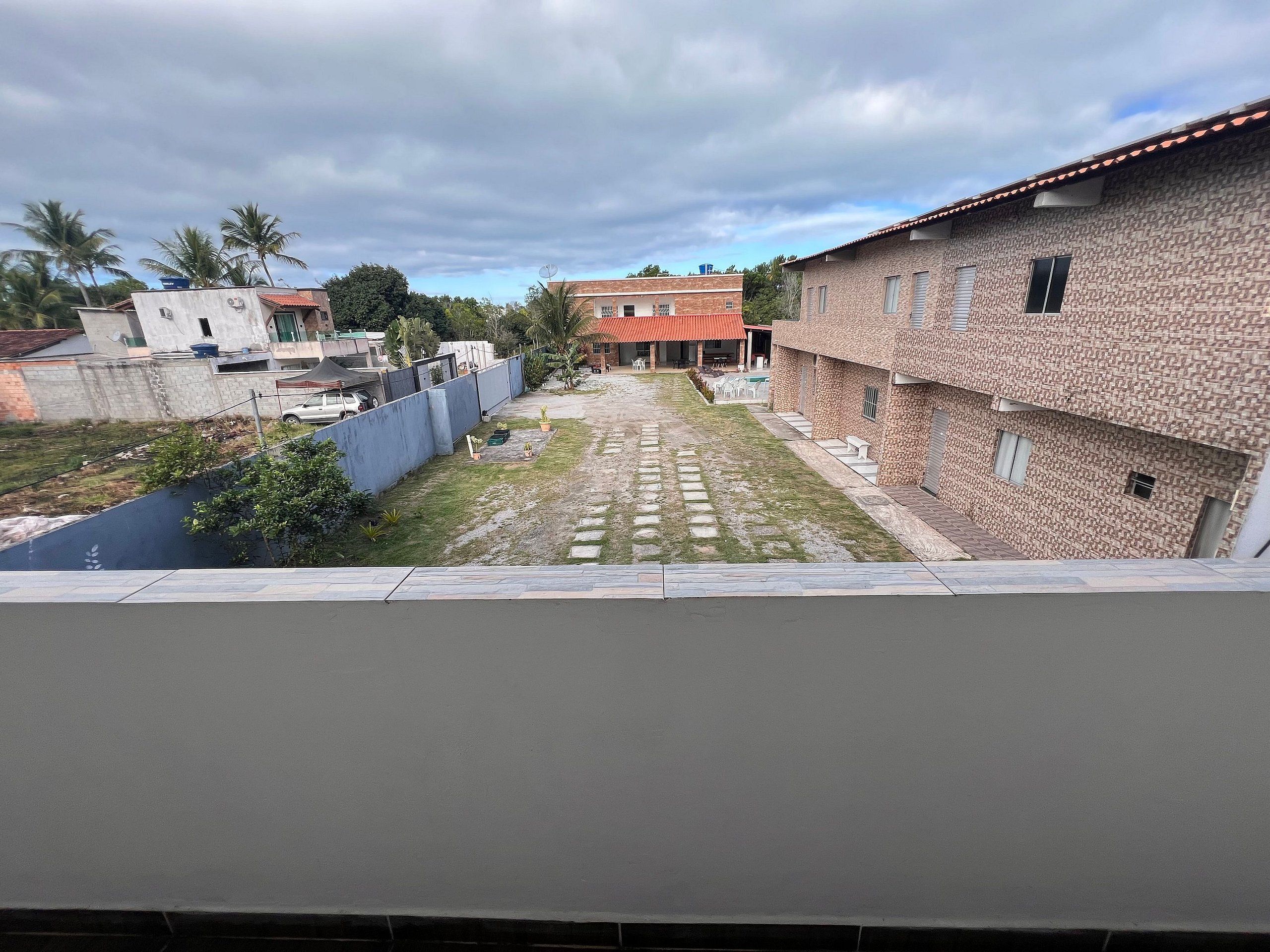 Un patio con un sendero empedrado, una fuente pequeña y un edificio de ladrillo con techo rojo.