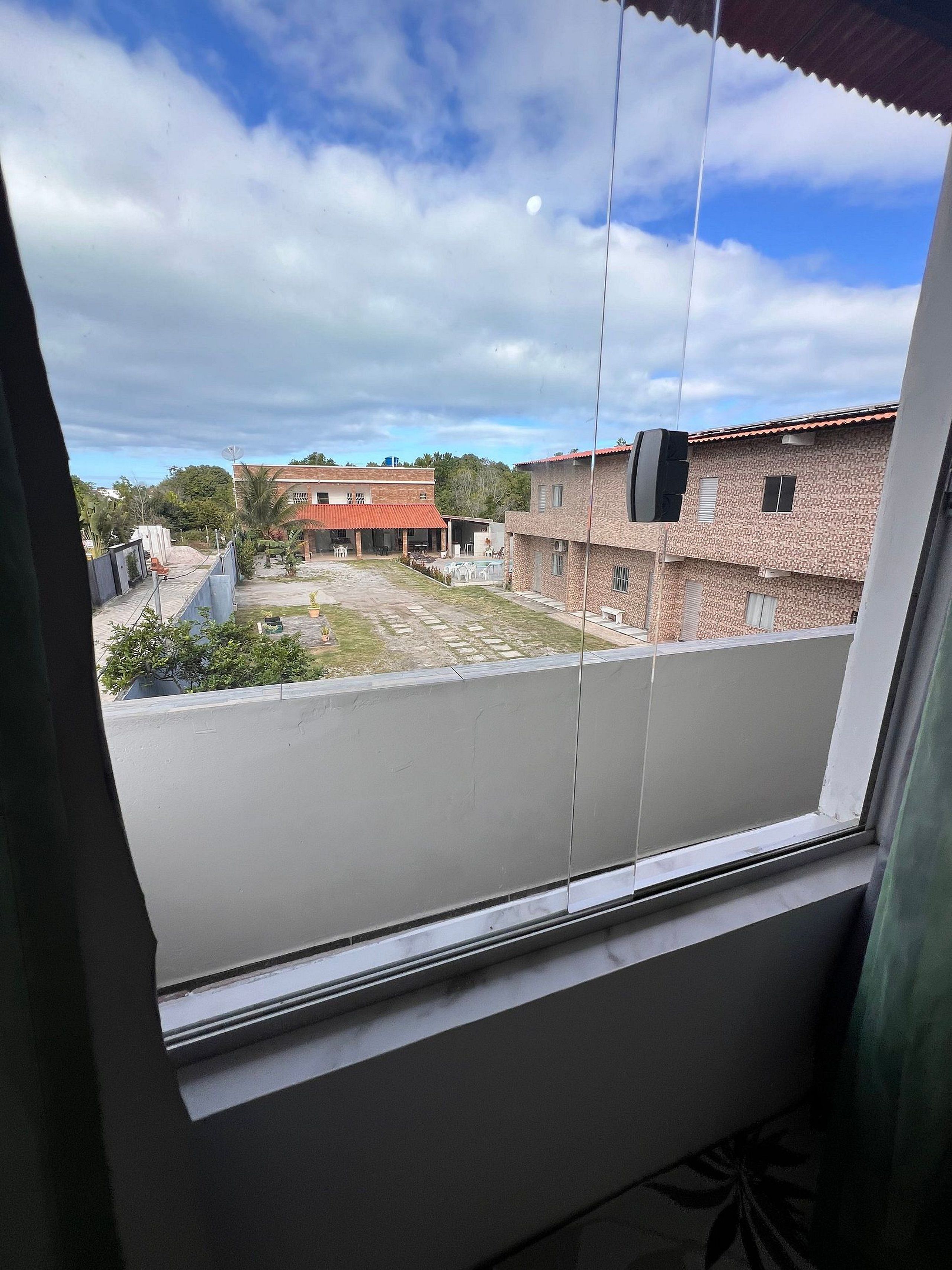 A view from a window overlooking a courtyard with buildings, a satellite dish, and a clear sky.
