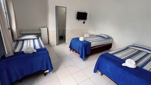 Habitación de hotel con tres camas, televisión y aire acondicionado.