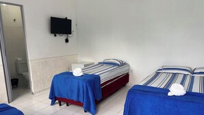 Habitación de hotel con dos camas, un televisor montado en la pared y un baño visible a través de una puerta abierta.