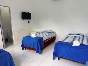 Habitación de hotel con dos camas, un televisor montado en la pared y un baño visible a través de una puerta abierta.