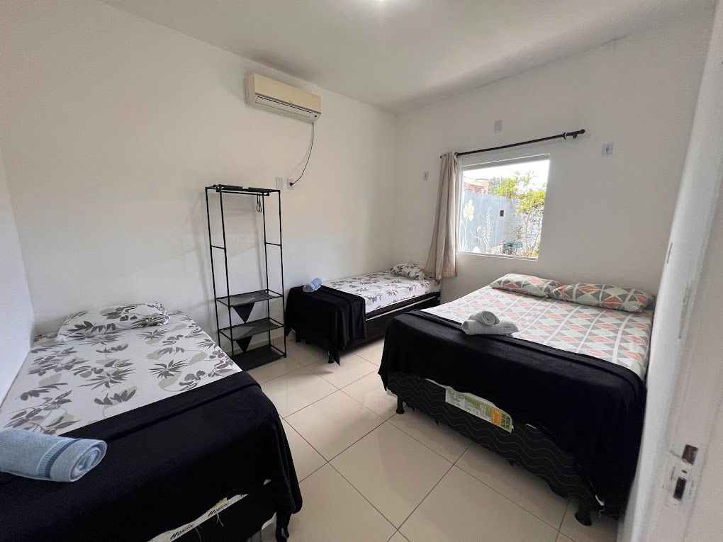 A room with two beds, a window, and an air conditioning unit.