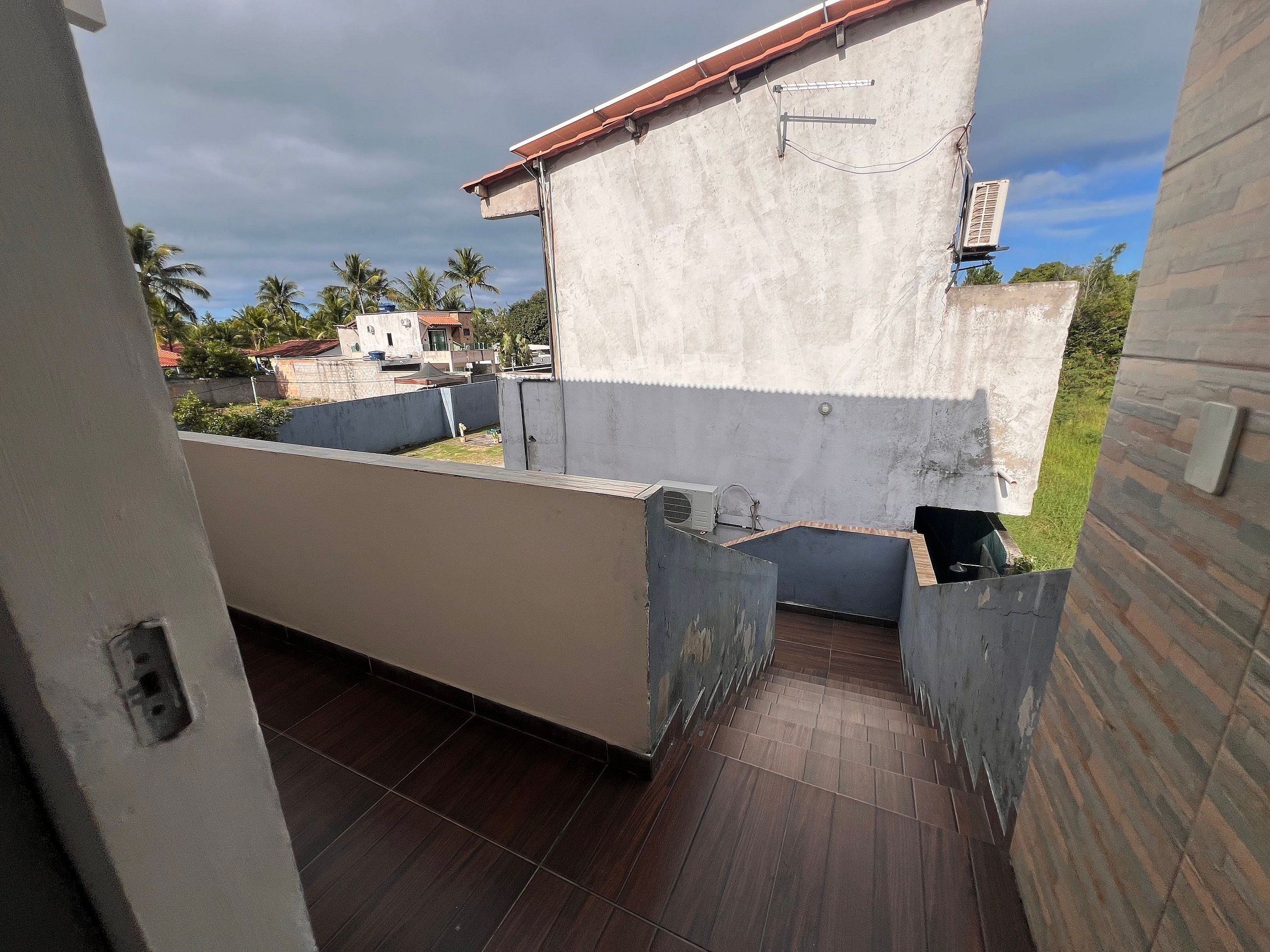 A balcony with a view of neighboring buildings and a clear sky.