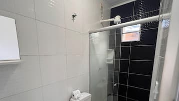 A bathroom with a toilet, bidet, and glass-enclosed shower.