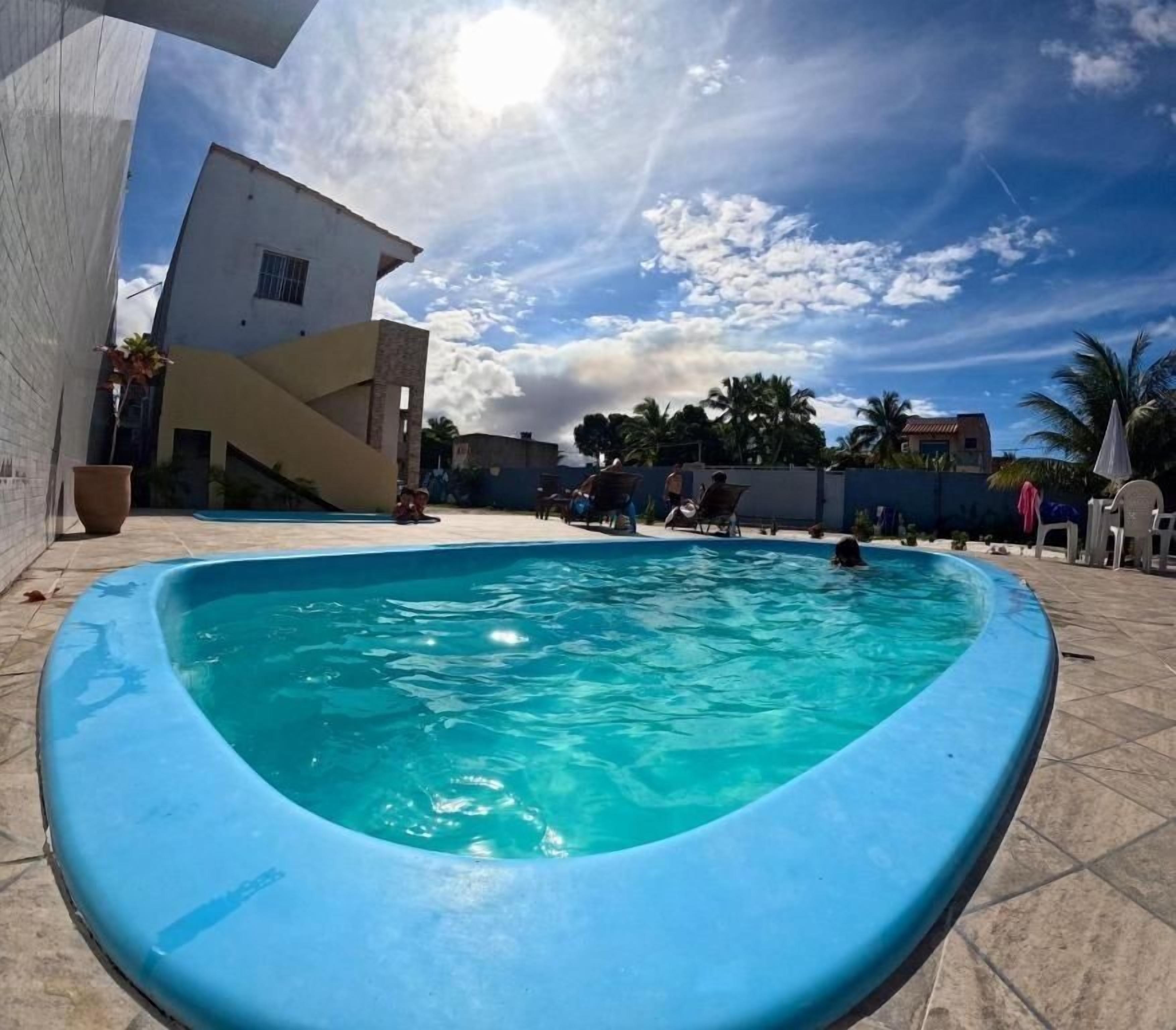 A swimming pool with a curved edge, surrounded by a tiled patio.
