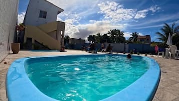 Una piscina a forma curva, circondata da un patio piastrellato.