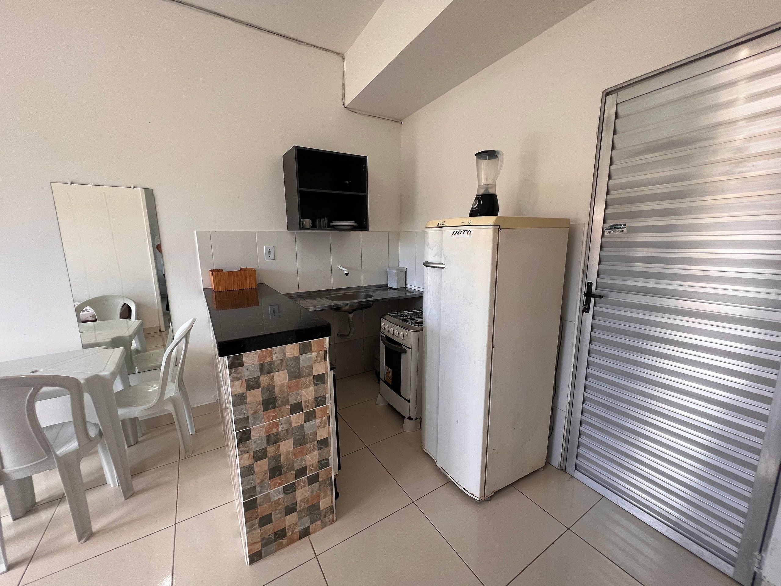 Une cuisine compacte équipée d’un réfrigérateur, d’une cuisinière, d’un évier et d’un coin repas avec des chaises.