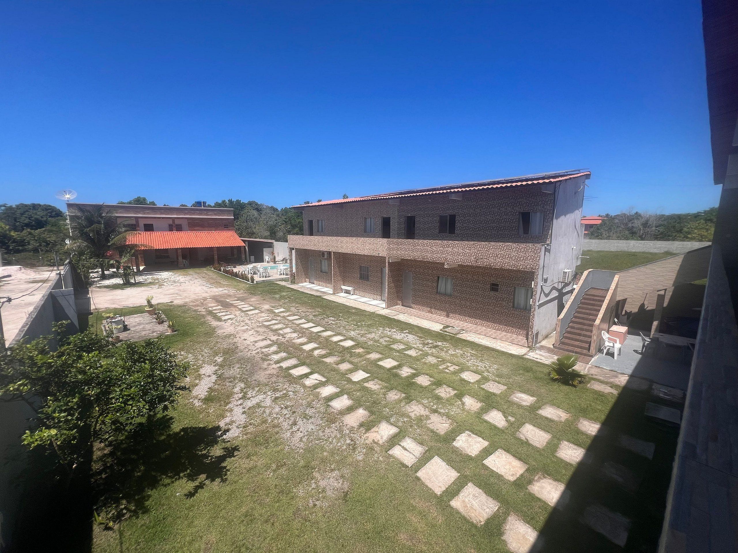 A courtyard with a paved area, a building with a tiled roof, and a staircase leading to an upper level.