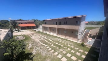 Un patio con área pavimentada, un edificio de techo a tejas y una escalera que conduce a un nivel superior.
