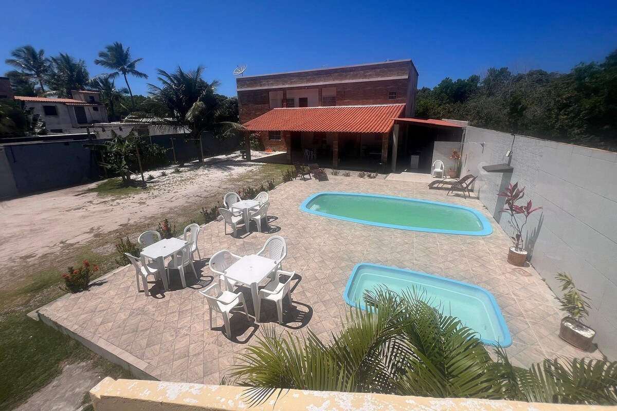 Zona residencial con piscina, mobiliario de exterior y un edificio de techo rojo.