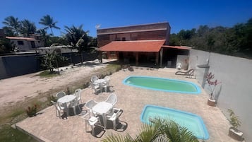 Zona residencial con piscina, mobiliario de exterior y un edificio de techo rojo.