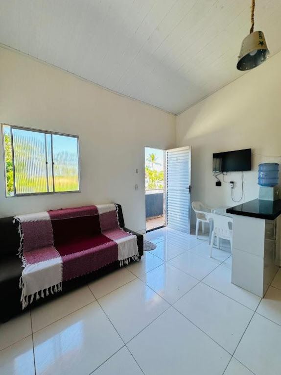 Una sala de estar con sofá, televisor, dispensador de agua y puerta corrediza de vidrio que da a un balcón.