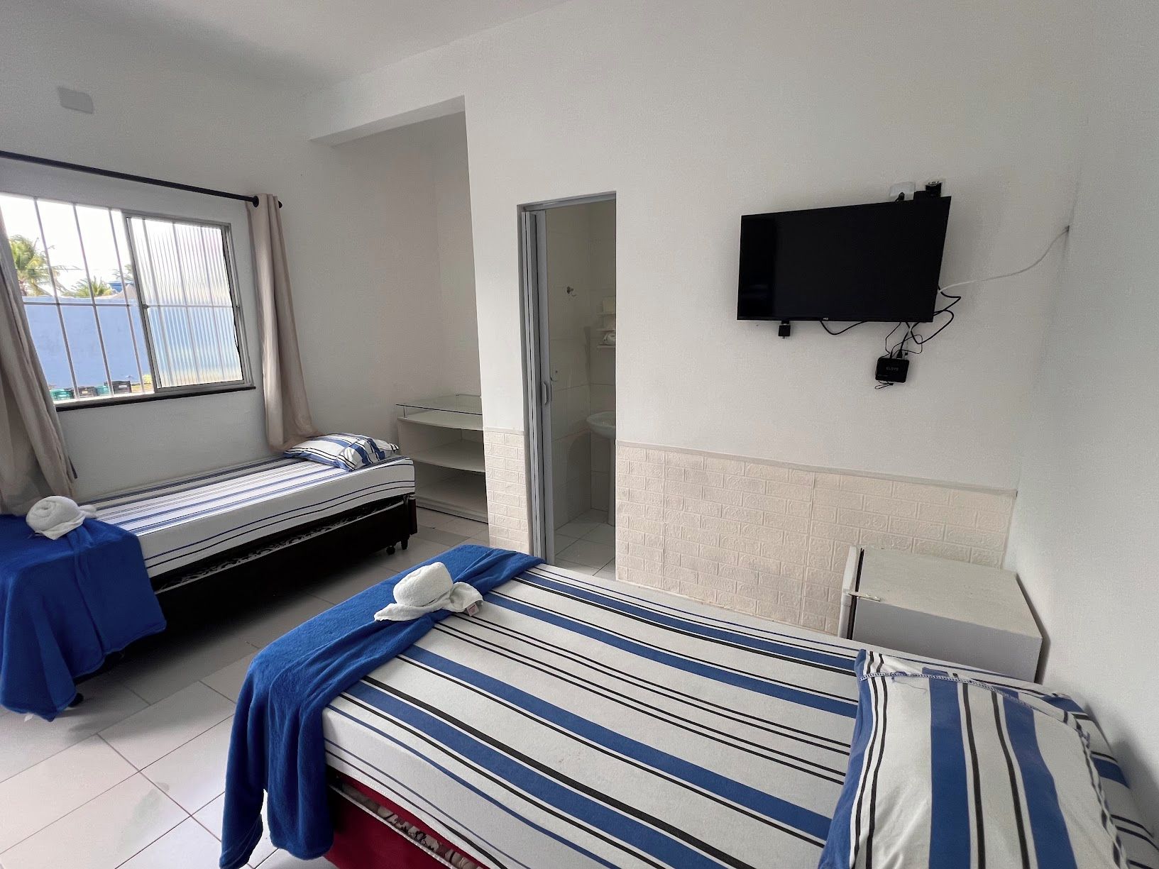 Ein Hotelzimmer mit zwei Betten, einem Fernseher und einem Badezimmer.
