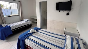 Habitación de hotel con dos camas, televisor y baño.