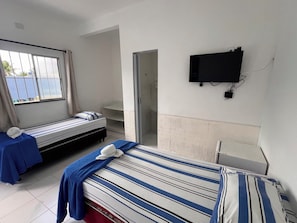 Habitación de hotel con dos camas, televisor y baño.