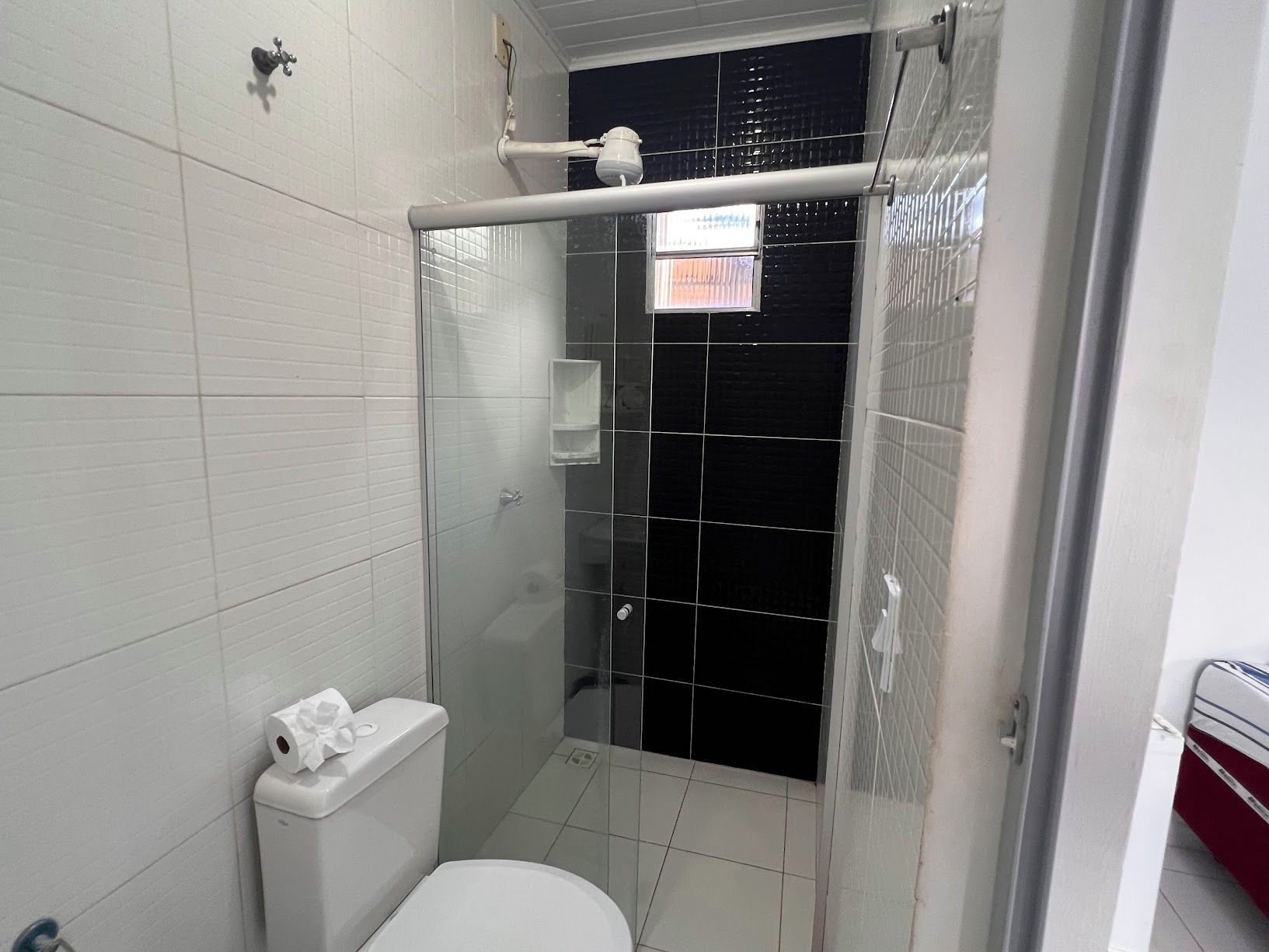 A bathroom with a white toilet, a glass shower enclosure, and a white sink.